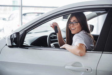 Young happy woman near the car with keys in hand