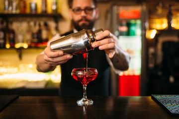 Barman is making alcohol cocktail at counter