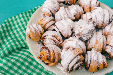 Homemade fresh cookies dusted powdered sugar in white plate on wooden blue background and napkin.
