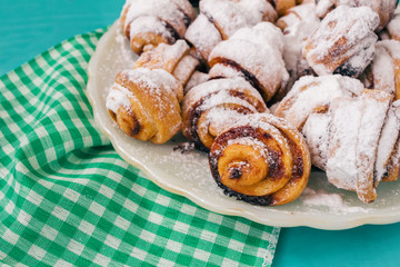 Homemade fresh cookies dusted powdered sugar in white plate on wooden blue background and napkin.