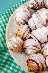 Homemade fresh cookies dusted powdered sugar in white plate on wooden blue background and napkin.