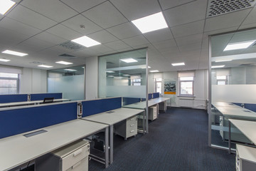 Fototapeta na wymiar Modern office interior with multiple open-plan work stations at long desks