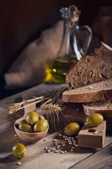 Foto op Plexiglas Fresh multigrain crusty bread, green olives and wheat ears on a rustic wooden table. © svittlana