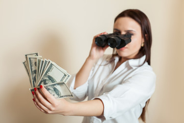 Woman looks through binoculars on money fan 