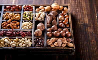 Nuts Mixed in a Wooden Vintage Box.Assortment, Walnuts,Pecan,Peanuts,Almonds,Hazelnuts,Macadamia,Cashews,Pistachios.Concept of Healthy Eating.Vegetarian.Copy space.selective focus.