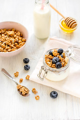 Homemade granola with blueberries in jar on white kitchen background