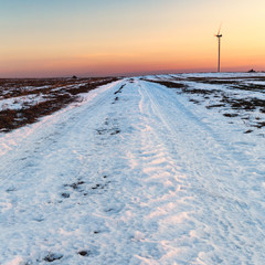 Wintry Field in Snow with a Single Wind Turbine in Background