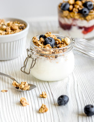 Homemade fitness granola with yoghurt and berries on white kitchen background