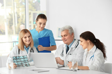 Fototapeta premium Team of doctors exploring roentgenogram at table