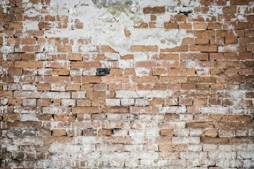 Fragment of old brick wall with multicolored bricks and the plaster showered, background