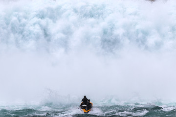 Jet skier riding into a giant wall of water from a dam spillway
