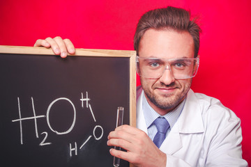 Scientist checking the quality of the water. He is holding blackboard with water chemical formula on it.