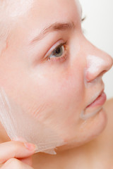 Woman removing facial peel off mask closeup