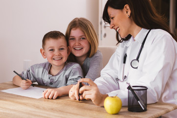 Beautiful female doctor playing with kids at doctor's. Doctor isn't scary.