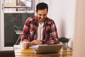 Handsome man working on laptop at home office.