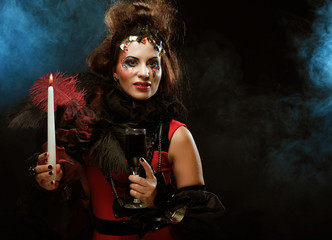 Young woman wearing carnival costume holding a candle. 