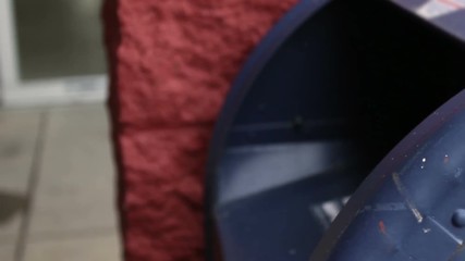 Man delivers envelope into mailbox near supermarket   Close up