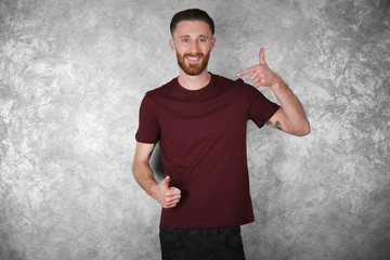 Young handsome man in claret red T-shirt on colour textured wall background