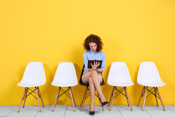 Young woman waiting for job interview on yellow wall background