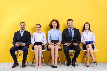 Group of people waiting for job interview on yellow wall background