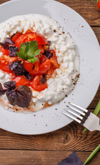 Salad with cottage cheese and tomatoes on wood table.