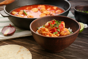 Chicken tikka masala with rice in bowl on wooden table
