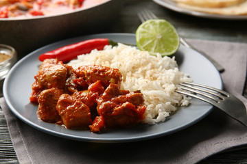 Portion of chicken tikka masala with rice in plate on grey napkin