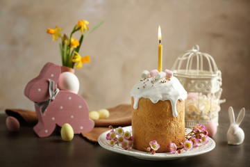 Easter cake with lighted candle on table