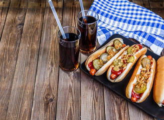 American hot dog with pickles,onions, ketchup, mustard and two soda
