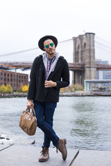 Young entrepreneur with a casual outfit, with boots and a briefcase in Brooklyn, New York