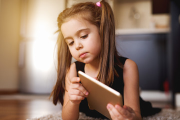 Charming girl relaxing after classes laying on floor with tablet.