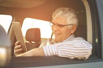 Fototapeta premium Senior man using digital tablet in a car.