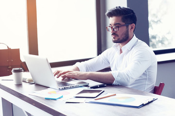 young hipster businessman working on laptop at modern office.