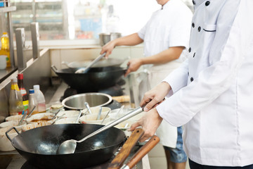 Group of chefs in hotel or restaurant kitchen busy cooking