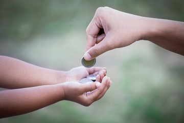 Mother giving coin to child as saving money concept in vintage color tone