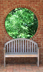 Trees through round window and wood bench