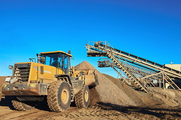 Yellow Bulldozer Working in the background of sky and gravel hills.