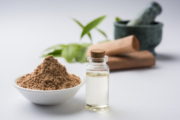 Chandan or sandalwood powder with traditional mortar, sandalwood sticks, perfume or oil and green...