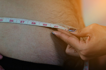 fitness girl measuring a big paunch of fat man ; he wanna be healthy body by exercise and body weight