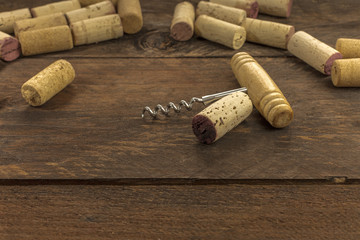 Old-fashioned corkscrew with corks on wooden background