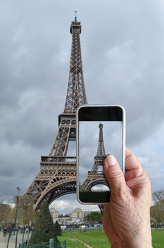 Seniors are shooting . old people taking pictures with his Smart Phone The Eiffel Tower the city in the background in Paris, France . During a trip to through Europe.