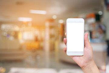 Woman hand holding mobile smart phone with hospital blurred for background