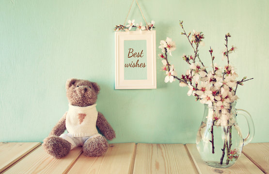 cute teddy bear sitting next to spring cherry tree