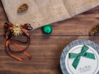 Vintage gift box, fir cones, Christmas toy, ribbon with bow on wood and burlap vintage background, photo top view. Copy space for text. Top view, Studio photography