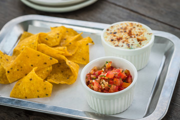 Salsa sauce with nacho chips and baked spinach with cheese