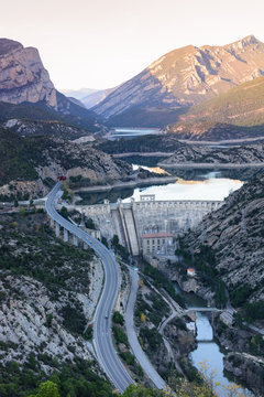 View of hydro-electric power station and a highway. Dam at Sege river, Oliana, Spain, Europe. Mountain peaks landscape.