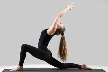 Young attractive yogi woman practicing yoga, stretching in Horse rider exercise, anjaneyasana pose,...