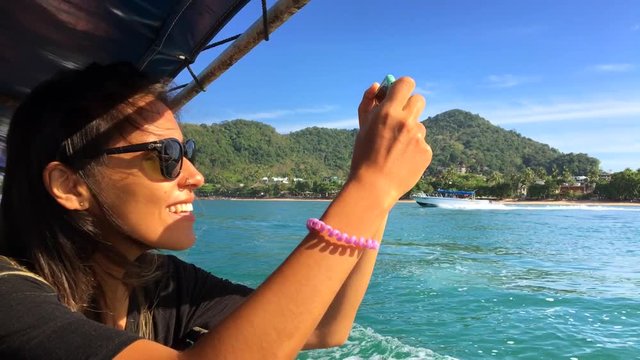 Young Happy Girl Sails on a Boat and Take Pictures on smart phone. Krabi, Thailand.