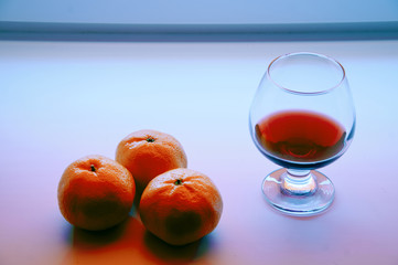 glass with the  wine and the manadrins on the window