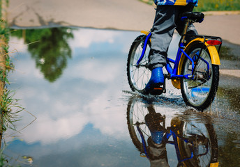 Obraz premium little boy riding bike in water puddle